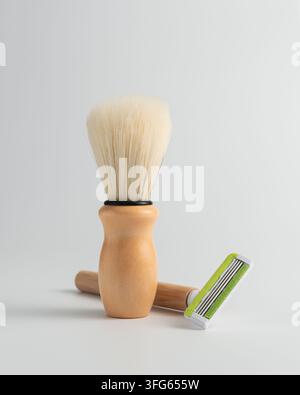 Klassische hölzerne Rasierbürste mit weißen Borsten und einem nachhaltigen Bambus-Rasiergriff auf einem hellgrauen Hintergrund. Minimalistisches Pflegeset für Null Abfall Stockfoto