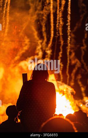 ABSTRAKTE DARSTELLUNG EINES MENSCHEN, DER EINE FEUERLICHE VORFÜHRUNG BEACHTET, DAS BRENNEN DER WEIDENMANN-EFFIGIE, GREEN MAN FESTIVAL, BRECON, WALES, UK, 2016: Eine Figur ist als Silhouette vor einem abstrakten, feurigen Hintergrund eines großen Feuers und kaskadierender Feuerwerke in der Dunkelheit zu sehen. Foto: Rob Watkins. INFO: Das Green Man Festival findet jährlich im Brecon Beacons im August statt. Es feiert Musik, Kunst, Literatur, Wissenschaft und familienfreundliche Kultur in einer wunderschönen Berglandschaft. Jedes Jahr endet das Festival mit dem rituellen Verbrennen der Weidenmann-Green-Man-Effigie. Stockfoto