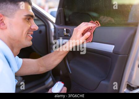 Der Fahrer reinigt das Innere der Autotür mit einem Mikrofasertuch Stockfoto