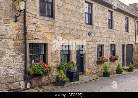 Scottage-Erbehaus im Denkmalschutzgebiet von Church Street, Kilbarchan, Schottland mit Blumenkästen, Blumen und Blumentöpfen. Stockfoto