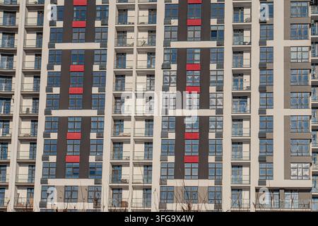 Modernes Apartmentgebäude mit optisch auffälligem Design Rot und Schwarz kontrastierende vertikale Linien erzeugen einen dynamischen Rhythmus auf der Außenseite, Interspers Stockfoto