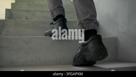 Bauarbeiter, Wander- oder Sicherheitsschuhe auf Stufen für Entwicklungscompliance und Schutz. PSA, Person und Stahlkappenstiefel auf der Baustelle mit Beinen Stockfoto