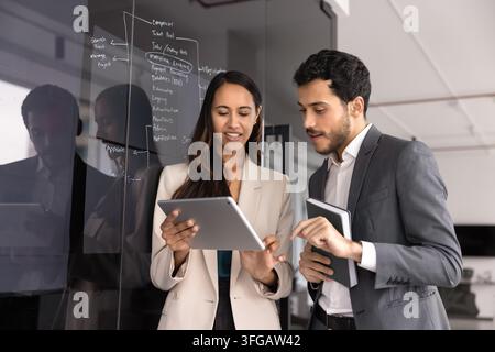 Teammitglieder überprüfen Projektdaten auf einem digitalen Tablet Stockfoto