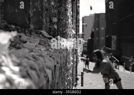 Ein Besucher fügt Kaugummi zur berühmten Kaugummiwand in der Post Alley in der Nähe des Pike Place Market hinzu, einer der bekanntesten öffentlichen Kunstattraktionen von Seattle. Stockfoto