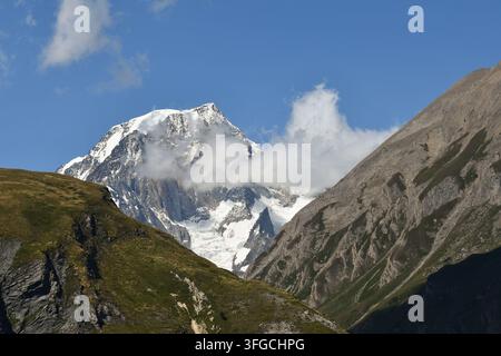 Schneebedeckter Gipfel des Mont Blanc teilweise von Wolken bedeckt hinter Bergkämmen. Kleiner Sankt-Bernhard-Pass, La Thuile, Aostatal, Italien Stockfoto