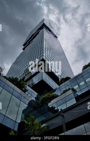 Abstrakte Perspektive eines zeitgenössischen Glas- und Stahl-Großstadt-Wolkenkratzers, der in einen dramatischen bewölkten Himmel einer modernen Metropole ragt Stockfoto