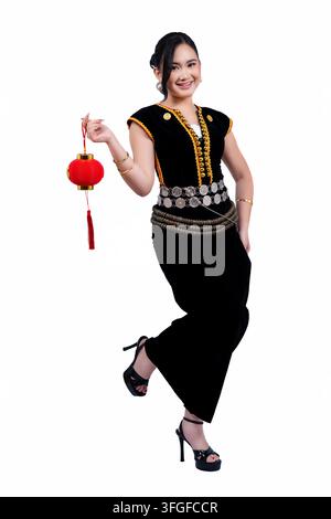Junge Frauen in traditioneller Kadazan-Dusun-Bekleidung halten eine rote chinesische Laterne auf weißem Hintergrund Stockfoto
