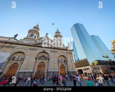 SANTIAGO, CHILE - 03. DEZEMBER 2025: Menschen gehen an der historischen Metropolitankathedrale von Santiago und dem modernen Glaskoloss an der Plaza de Armas vorbei Stockfoto
