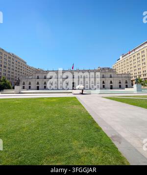 SANTIAGO, CHILE - 03. DEZEMBER 2025: Die große Fassade des La-Moneda-Palastes erhebt sich hinter einem grasbewachsenen Platz an der Plaza de la Ciudadania unter einem klaren blauen Himmel in Stockfoto