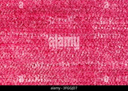 Eine Nahaufnahme einer lebhaft rosa getufteten Teppichoberfläche mit dichten Faserbündeln und weicher Beleuchtung. Stockfoto