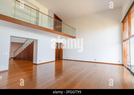 Modernes Luxus-Loft-Interieur: Eine geräumige, lichtdurchflutete Loft-Wohnung mit polierten Holzböden, hohen Decken und einer minimalistischen Treppe Stockfoto