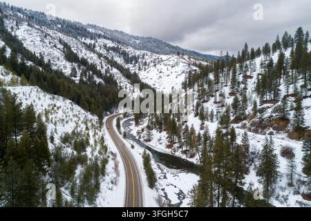 Winterstraße schlängelt sich durch schneebedeckte Kiefernwälder Stockfoto