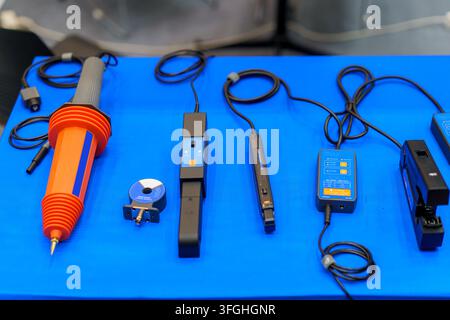 Eine Sammlung von elektrischen Testgeräten, einschließlich einer Hochspannungsprobe und verschiedener Klemmstromsensoren, die auf einer blauen Oberfläche für ind angezeigt werden Stockfoto
