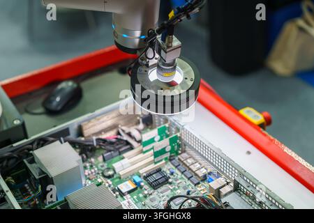 Nahaufnahme eines automatisierten industriellen Roboterarms, der mit einer hochauflösenden Maschinenbildkamera und einem LED-Ringlicht ausgestattet ist, während er die interne Kompo inspiziert Stockfoto