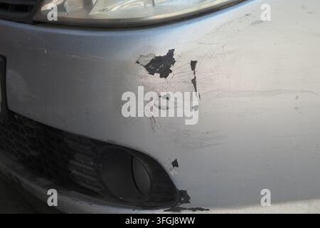 Schaden an der Stoßstange eines silbernen Autos, der im Parkbereich bei Tageslicht beobachtet wurde Stockfoto