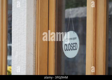 Ladenschild zeigt den geschlossenen Status auf einem Türfenster während des Tages Stockfoto