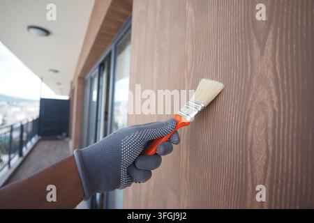 Person malt eine hölzerne Wand auf einem Balkon in einer Stadtszenerie Stockfoto