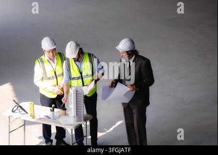 Immobilienentwickler betrachten ein architektonisches Modell auf einer leeren Etage einer Baustelle, Hochwinkelaufnahme von leitenden Baustellenmanagern und Ingenieuren Stockfoto