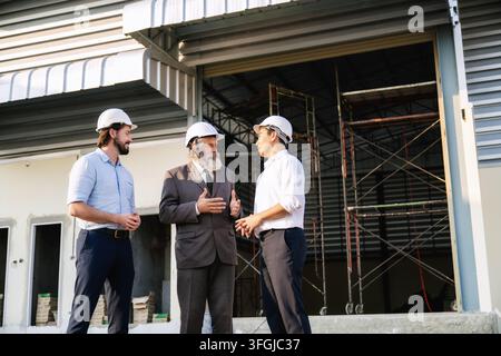Senior-Manager diskutiert mit Bauingenieuren bei der Arbeit an einer Lagerhalle. Konzept des Immobilienbaus für Lagerprojekte Stockfoto