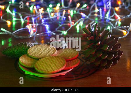 Bunte dekorative Weihnachtslichter, Kekse und herbstliche Tannenzapfen. Stockfoto