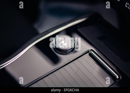 Makrodetail des Multimediaknopfes mit Wiedergabe- und Pausesymbol auf der Mittelkonsole eines modernen Autointerieurs. Stockfoto