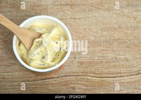 Eiscreme mit Vanille-Schokoladenstückchen-Geschmack in einem Pappbecher mit Holzlöffel auf dem Tisch Stockfoto