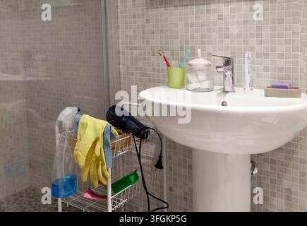 Weißes Keramik-Pedestalwaschbecken mit Chrom-Wasserhahn und persönlichen Hygieneaccessoires. Stockfoto