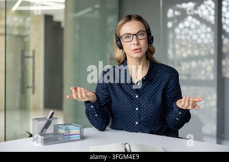 Ferngeschäftskommunikation und virtuelles Meeting, professionelle Frau mit Headset spricht während eines Videoanrufs im Büro zur Kamera. Stockfoto