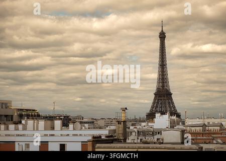 Eiffelturm erhebt sich über den Dächern von Paris unter einem dramatischen bewölkten Himmel, Panoramablick auf die Stadt Paris, Frankreich Stockfoto