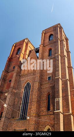 Niedrigwinkelaufnahme der massiven roten Backsteinfassade und der beiden Türme der Kathedrale der heiligen Maria Magdalena in Breslau, Polen Stockfoto