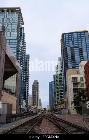 Bahnstrecken in der Innenstadt von San Diego mit großen Wolkenkratzern, die die Bahnlinie an einem bewölkten Tag umgeben Stockfoto