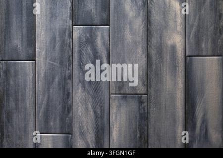 Dunkelgraue Holzwandpaneele mit natürlicher Maserung. Dunkelgraue Holzpaneele vertikal angeordnet mit sichtbarer Maserung, Nähten und einer verwitterten Oberfläche Stockfoto