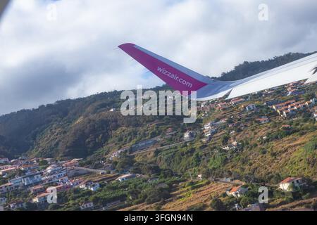 Madeira, Portugal, 5. August 2026 – Wizz Air-Flugzeug startet über Häusern auf einem Hügel in der Nähe des Flughafens Madeira Stockfoto