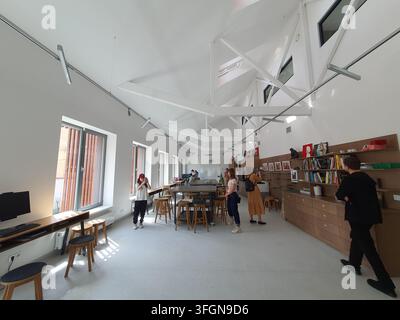 Ein helles, geräumiges Interieur eines modernen Studios, Klassenzimmers oder kreativen Arbeitsbereichs mit hohen Gewölbedecken und freiliegenden weißen Strukturträgern Stockfoto