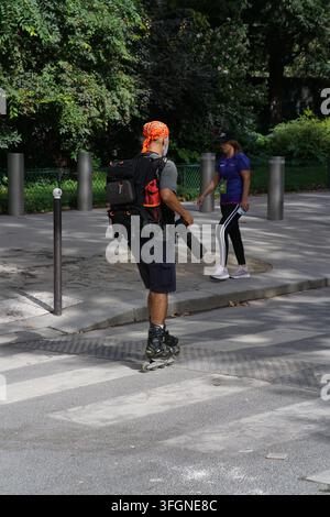 Mann auf Rollerblades, der Kamerageräte trägt, neben Teilnehmern während des Frauenlaufs La Parisienne in Paris, Frankreich. Stockfoto