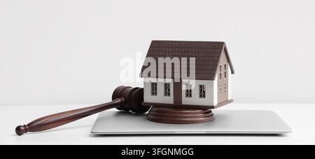 Immobilienrecht und Eigentumsstreitigkeiten, hölzerner Richterhammer mit Hausmodell auf Laptop für Rechtsberatung und Lösung von Wohnungsstreitigkeiten im Büro Stockfoto