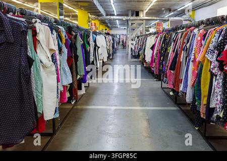 Secondhand-Kleiderladen, farbenfrohe gebrauchte Kleidungsstücke, die in Regalen im Secondhand-Laden hängen, Wiederverkaufsmode, erschwingliches Einkaufen, Wiederverwendung und Kreislaufwirtschaft. Stockfoto