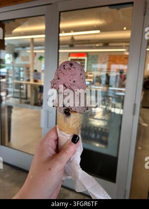 Frau hält eine Eiswaffel mit zwei Kugeln in einem Geschäft Stockfoto