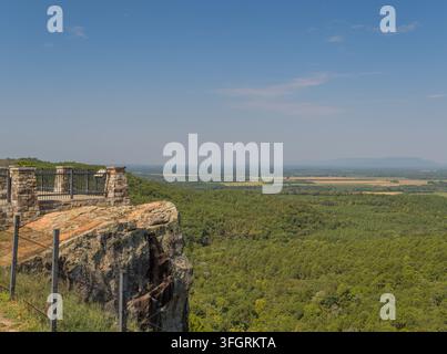 Eine steinerne Aussichtsplattform mit Metallgeländern steht auf einer felsigen Klippenkante mit Blick auf ein weites bewaldetes Tal. Stockfoto