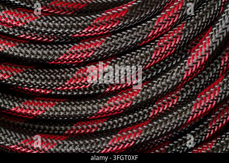Rot-schwarzes Kabel zum Verbinden elektronischer Geräte. Nahaufnahme der Kabeltextur. Stockfoto