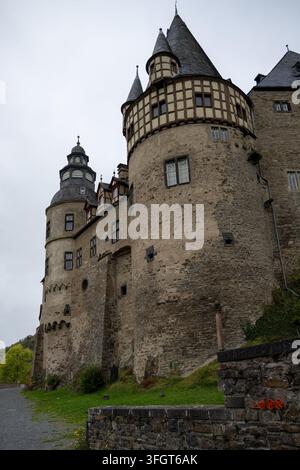 Niedrigwinklige Außenansicht von Steintürmen, halbverkleideten Obergeschossen, Schieferdächern und kegelförmigen Türmchen am Schloss Bürresheim in Rheinland-Pfalz. Stockfoto