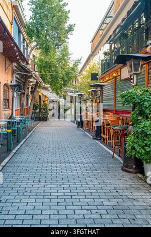 Fußgängerzone mit Straßencafés, Restaurantterrassen, Holztischen, Bäumen und traditionellen Gebäuden in Athen, Griechenland. Urbane Tourismus Stockfoto