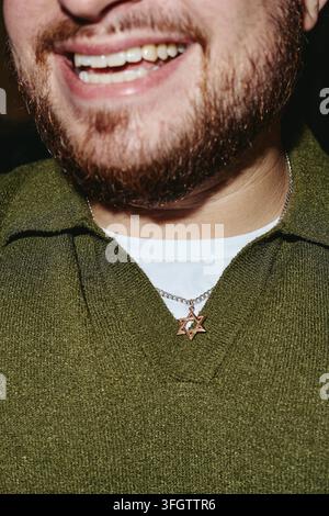 Lächelnder bärtiger Mann mit Stern-von-David-Halskette drinnen Stockfoto