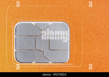 SIM-Karte auf orangefarbenem Hintergrund. Makroaufnahme Stockfoto