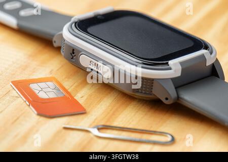 Smartwatch und SIM-Karte auf einem Holztisch Stockfoto