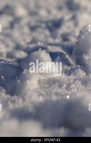 Die schneebedeckte weiße Oberfläche einer Winter-Schneeverwehung, die Reliefschicht zeigt die komplexe Geometrie von Eiswachstum an einem frostigen Tag Stockfoto