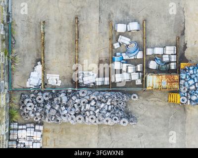 Luftaufnahme von Stapeln aus Schrottmetallspulen und Industrieabfall, die auf einem Betonhof in Taiwan gelagert sind. Stockfoto