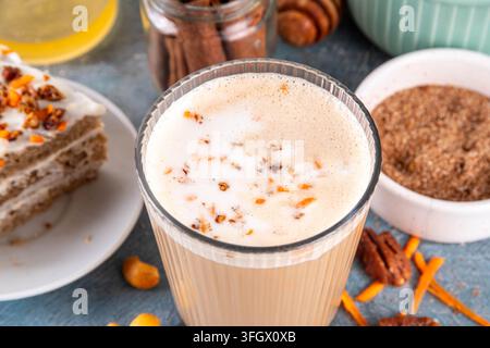 Leckerer Herbst-Karottenkuchen oder Karotten-Gewürz-Cappuccino, belegt mit geschlagener Sahneschaumcreme, süßem Sirup, zerkleinerten Pekannüssen und in Scheiben geschnittenen Karotten, mit Zimt Stockfoto