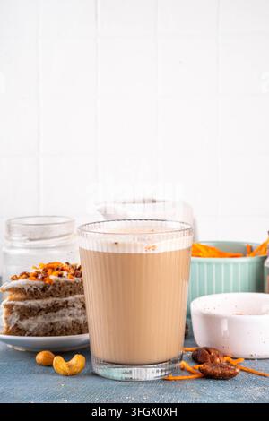Leckerer Herbst-Karottenkuchen oder Karotten-Gewürz-Cappuccino, belegt mit geschlagener Sahneschaumcreme, süßem Sirup, zerkleinerten Pekannüssen und in Scheiben geschnittenen Karotten, mit Zimt Stockfoto