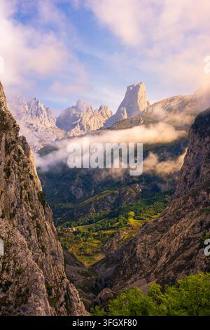 Blick auf die dramatischen Felsgipfel der Picos de Europa-Berge mit tief hängenden Wolken, üppigen grünen Tälern und steilen Kalksteinklippen in Spanien Stockfoto